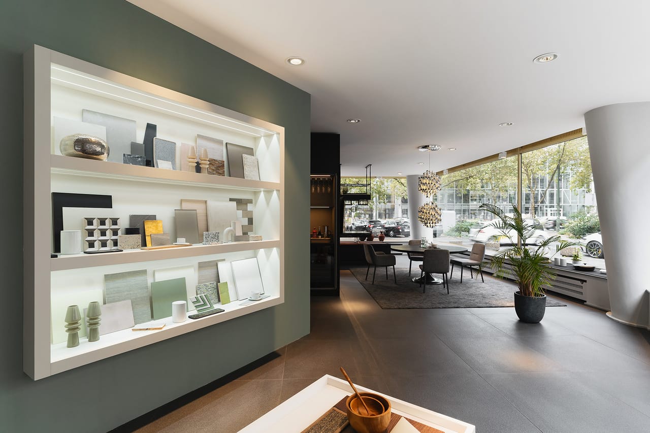 The studio showroom, with the lit sample wall on a green wall and the dining area beyond